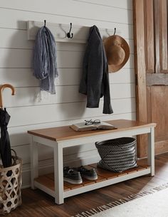 a coat rack with umbrellas and shoes on it next to a wooden bench in front of a door