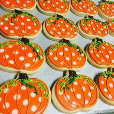 many decorated pumpkin cookies on a tray