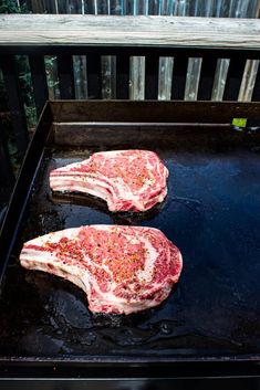 two raw steaks are cooking on an outdoor grill