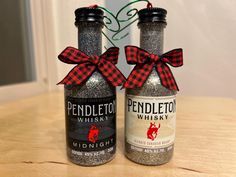 two bottles with red and black bows on them sitting on top of a wooden table