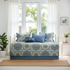 a living room filled with furniture and pillows on top of a rug in front of a window