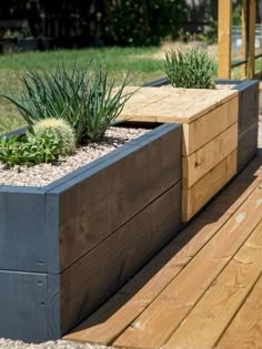 two wooden planters sitting on top of a wooden deck next to grass and trees