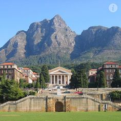 a large building in the middle of a grassy area with mountains in the back ground