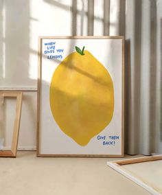 there is a yellow lemon on the table next to two framed pictures and a small wooden frame