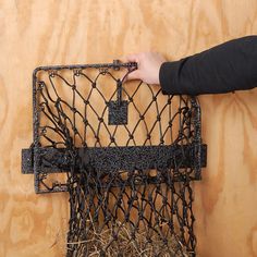 a person holding a piece of wire in front of a wooden wall