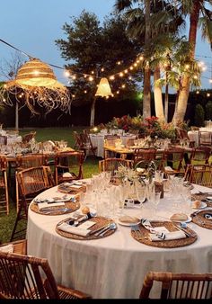 an outdoor dining area with tables and chairs, lights strung from the ceiling, and palm trees