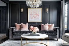 a living room with black walls, pink pillows and a chandelier hanging from the ceiling