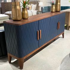 a blue cabinet with two gold vases on top and some chairs in the background