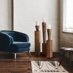 a blue chair sitting on top of a hard wood floor next to a white brick wall