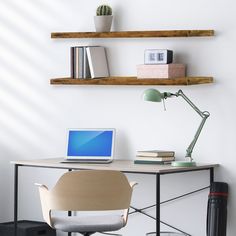 a laptop computer sitting on top of a wooden desk next to a lamp and bookshelf