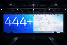 a large screen with the number forty4 on it in front of an auditorium full of people