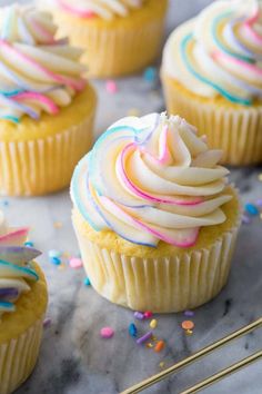 cupcakes with white frosting and sprinkles on a marble surface