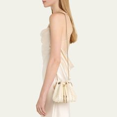 Jimmy Choo "Bon Bon" bucket bag in allover pearly satin viscose, brass, and ABS Flat metal top handle  Drawstring closure  Approx. 5.9"h x 5.5"W x 3.7"D Item Weight (Lbs.): 1.0 Made in Italy Beige Evening Bags With Bamboo Handle, Beige Evening Bag With Bamboo Handle, Beige Evening Shoulder Bag With Bamboo Handle, Evening Beige Bag With Bamboo Handle, White Bucket Bag For Evening, Chic Evening Pouch Bucket Bag, Luxury White Evening Bucket Bag, Formal Beige Shoulder Bag With Bamboo Handle, Elegant Bucket Evening Bag With Gold-tone Hardware