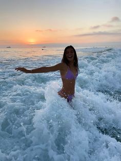 a woman standing in the ocean waves with her arms out and smiling at the camera