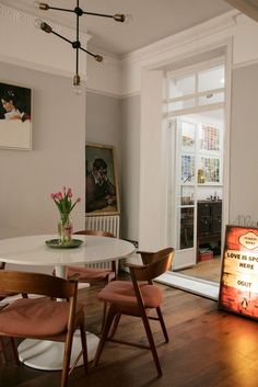 a dining room table with four chairs and a sign on the wall next to it