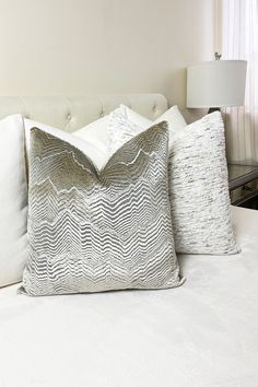 two white pillows sitting on top of a bed next to a lamp in a bedroom