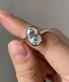 a person holding a ring with a diamond in it's middle and one hand