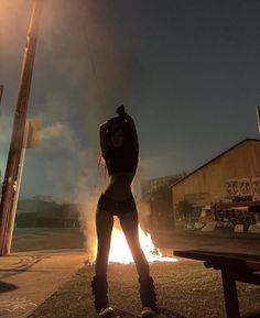 a woman standing in front of a fire