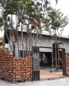 there is a large pile of wood in front of a building with palm trees around it