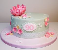 a birthday cake with pink flowers on the top and number 90 on the bottom, sitting on a white table