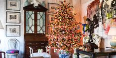 a living room with a christmas tree in the corner and pictures on the wall behind it