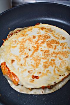 two pizzas sitting in a frying pan on top of a stove burner