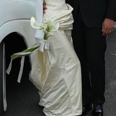 a bride and groom standing next to a white car