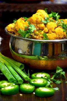 a bowl filled with cauliflower next to green peppers and jalapenos