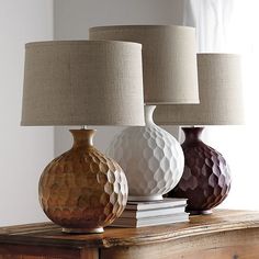 three different colored vases sitting on top of a wooden table next to a lamp