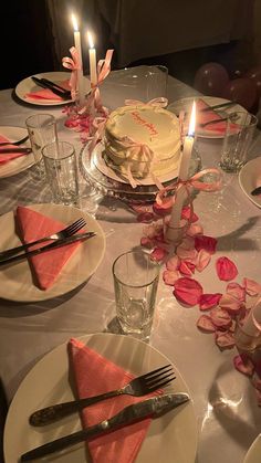 the table is set with plates, silverware, and pink napkins on it