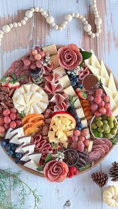 a platter filled with different types of cheese and meats next to pine cones