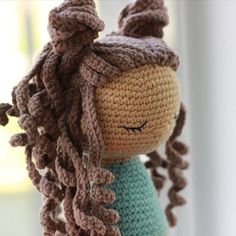 a crocheted doll with long hair is hanging from a hook on a window sill