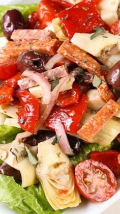 a salad is shown with tomatoes, olives, and other vegetables in it on a white plate