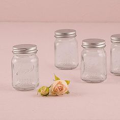 four mason jars with one rose on the side and three smaller ones in front, all lined up