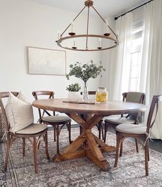 a dining room table with chairs around it and a vase on top of the table