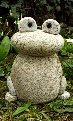 a frog statue sitting in the grass with two eyes on it's back legs