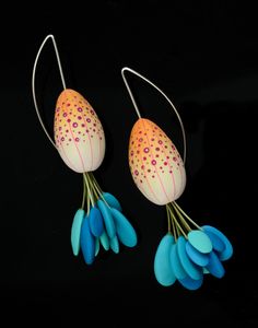 two pairs of earrings with blue and orange flowers hanging from it's hooks on a black background