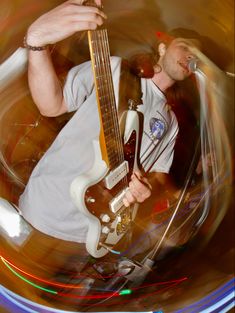 a man playing an electric guitar while standing in front of a microphone and some blurry lights