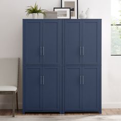 a blue cabinet in the corner of a room with a white chair and potted plant on top