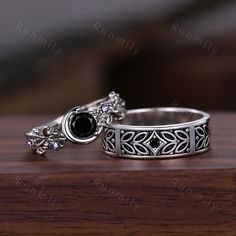 two silver rings with black stones on them sitting on a wooden table next to each other