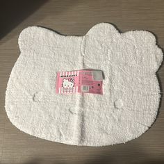 a hello kitty shaped toilet paper on top of a wooden floor next to a cell phone