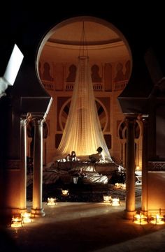 candles are lit in front of a large structure with columns and arches on the floor