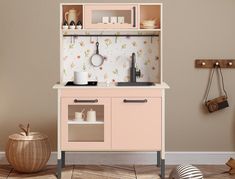 a toy kitchen with pink cabinets and white walls