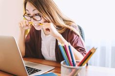 a woman sitting at a desk with a laptop and pencils in front of her