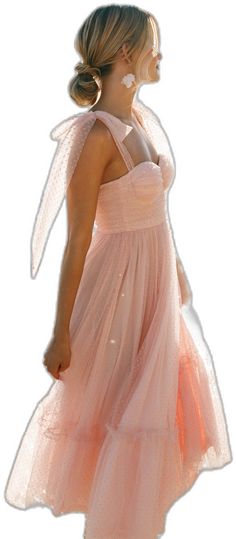 a woman in a pink dress is standing with her back to the camera and she's wearing an angel wing