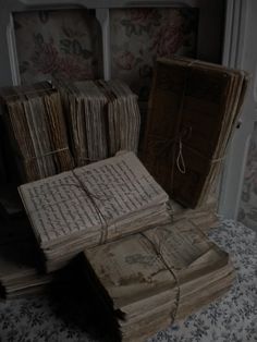 several old books are stacked on top of each other in a room with floral wallpaper