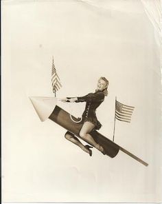 a woman flying through the air on top of a rocket with an american flag in the background