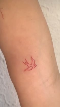 a small bird tattoo on the left side of the leg, with a red outline