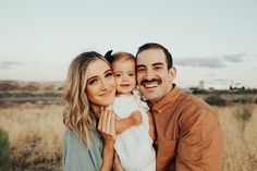 a man and woman holding a baby in a field