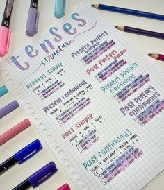 a notebook with some writing on it next to markers and pencils that say tense